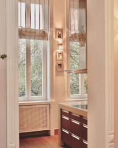 Wysokie okna, wpuszczają dużo światła, dobrze doświetlają pomieszczenie kuchenne w stylu vintage. Nowoczesne meble kuchenne z grubymi blatami, wykonane według projektu architekt wnętrz Anny Buczny. Fronty szafek kuchennych w ciemnym odcieniu, imitują drewno egzotyczne.