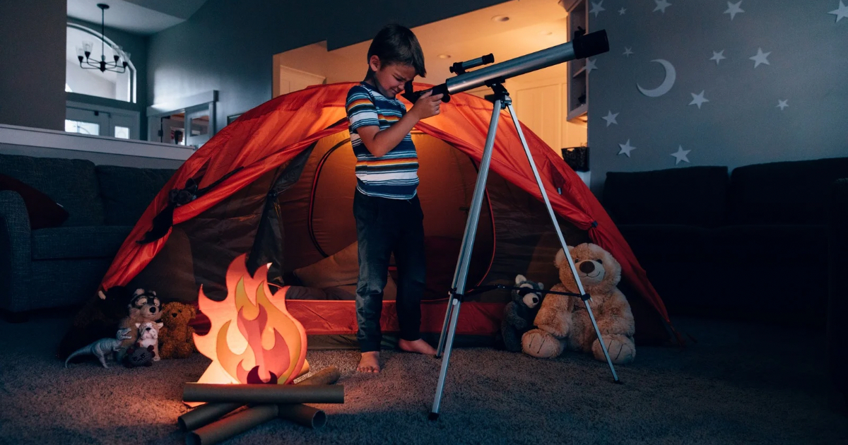 Pokój chłopca, który bawi się w otoczeniu zabawek, sztucznego ogniska, atrapy namiotu i teleskopu, spoglądając przez teleskop w namalowane na ścianach i suficie gwiazdy i księżyc. Architekt Anna Buczny w swoim artykule na blogu porusza kwestie projektowania pokoi dla dzieci. Aranżacja pokoju chłopca jest świetnym przykładem tego o czym w swoim artykule pisze projektantka wnętrz.