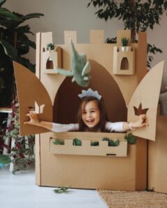 Dziewczynka przebrana za księżniczkę bawi się w swoim pokoju, w trakcie zabawy wygląda przez okno zamku wykonanego z kartonu. Jest w otoczeniu roślin i zabawek. Autorka artykułu o projektowaniu pokoi dla najmłodszych, architekt wnętrz Anna Buczny, posłużyła się tym jako przykład kreatywnego projektowania pokoi dla dzieci.